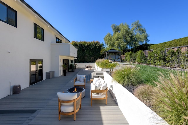 wooden terrace with an outdoor living space with a fire pit and a gazebo