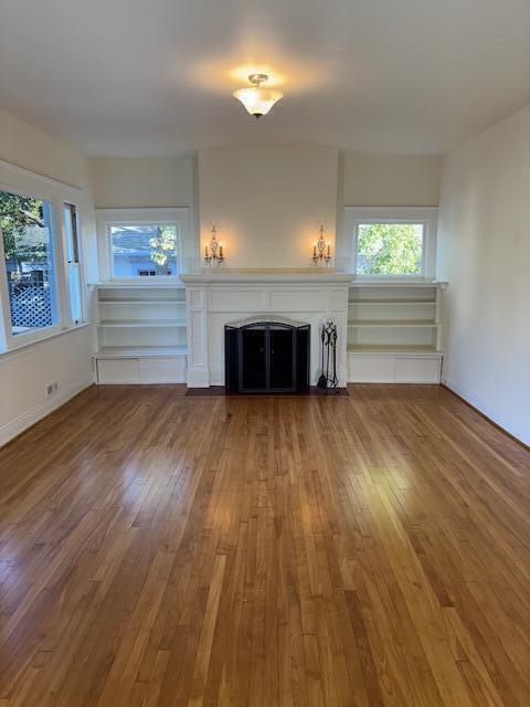 unfurnished living room featuring a wealth of natural light, a fireplace, and wood finished floors