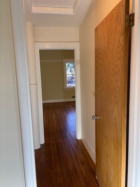 corridor with dark wood-style floors and baseboards