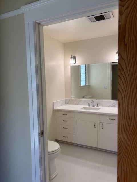 half bath with toilet, visible vents, and vanity