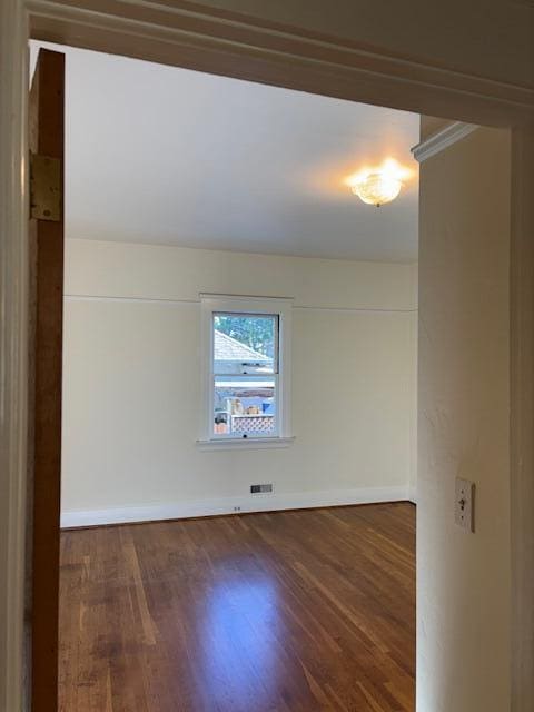 empty room with visible vents, baseboards, and dark wood-type flooring