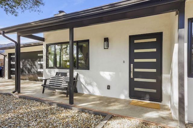 entrance to property featuring a patio and stucco siding