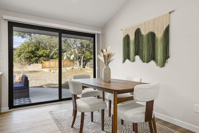 dining room with vaulted ceiling, baseboards, wood finished floors, and a healthy amount of sunlight