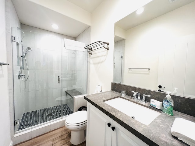 full bathroom featuring vanity, toilet, wood finished floors, and a shower stall