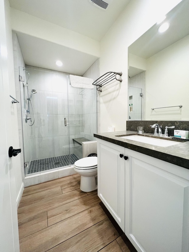 full bath featuring vanity, toilet, wood finished floors, and a shower stall