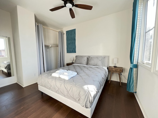 bedroom featuring a closet, baseboards, wood finished floors, and a ceiling fan