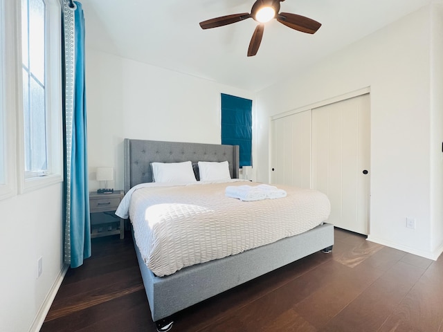 bedroom featuring a closet, baseboards, dark wood-type flooring, and a ceiling fan