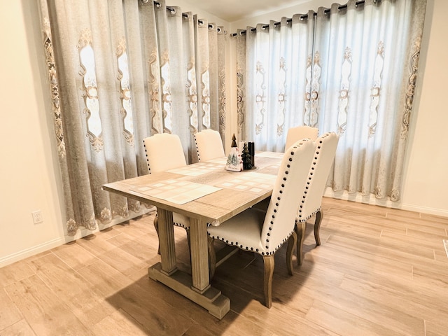 dining area featuring light wood-style flooring and baseboards