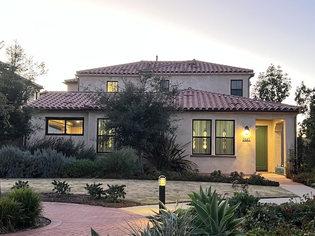 mediterranean / spanish home featuring stucco siding and a tiled roof