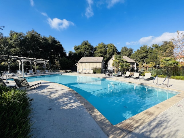 pool with a patio, fence, an outdoor structure, and a pergola