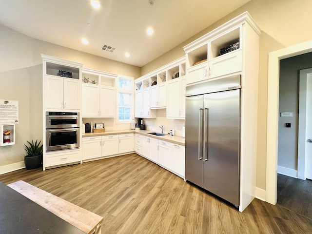 kitchen featuring visible vents, light wood-style flooring, open shelves, a sink, and stainless steel appliances