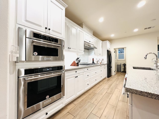 kitchen with visible vents, wood finish floors, stainless steel appliances, a sink, and under cabinet range hood