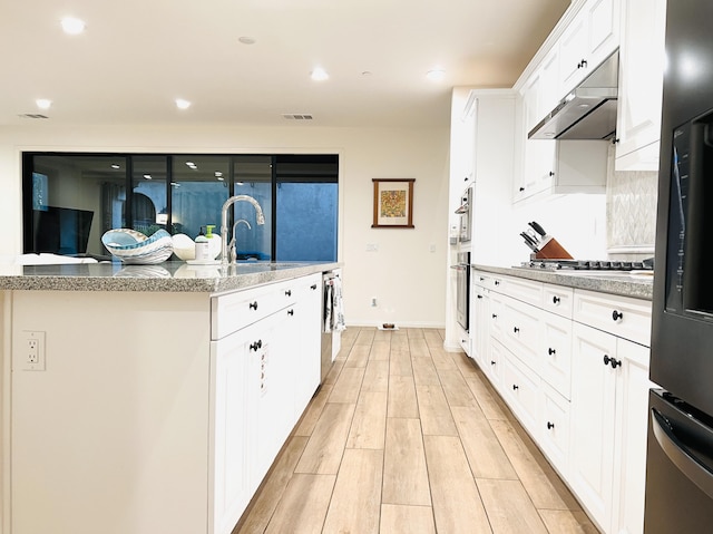 kitchen with visible vents, light wood-style flooring, under cabinet range hood, a sink, and appliances with stainless steel finishes