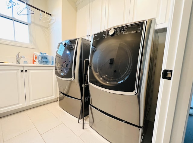 laundry area with cabinet space, light tile patterned floors, washer and dryer, and a sink