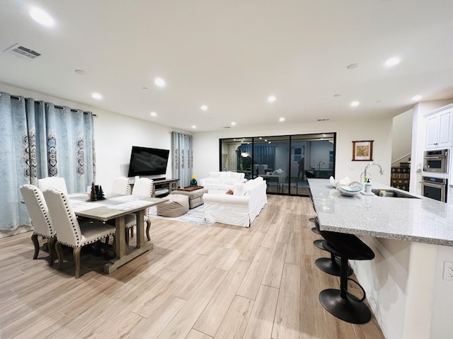 dining space featuring visible vents, recessed lighting, stairway, and light wood-style floors