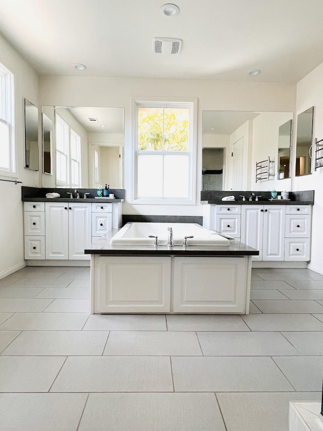 bathroom featuring a garden tub, two vanities, recessed lighting, and visible vents