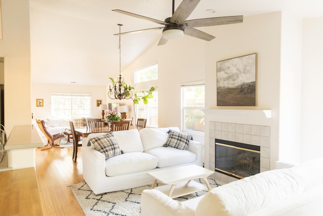 living area featuring high vaulted ceiling, a tile fireplace, plenty of natural light, and hardwood / wood-style floors