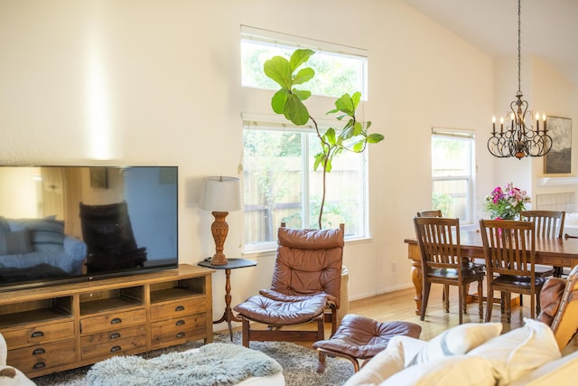 living area with high vaulted ceiling, an inviting chandelier, and wood finished floors