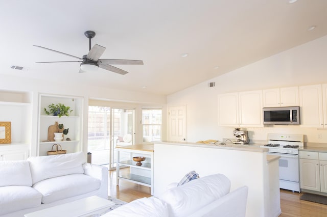 kitchen with visible vents, white range with gas stovetop, stainless steel microwave, and vaulted ceiling