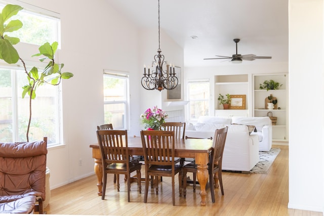 dining area with light wood finished floors, plenty of natural light, built in shelves, and vaulted ceiling