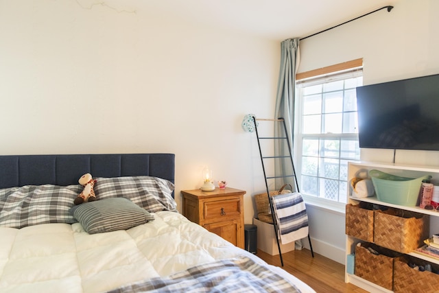 bedroom with multiple windows, baseboards, and wood finished floors