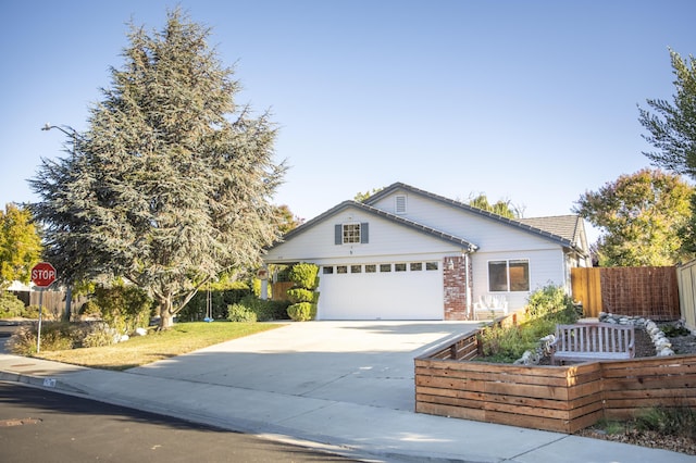 ranch-style home with driveway, brick siding, an attached garage, and fence