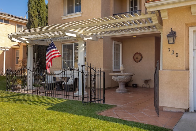 entrance to property featuring a pergola, fence, a lawn, and stucco siding