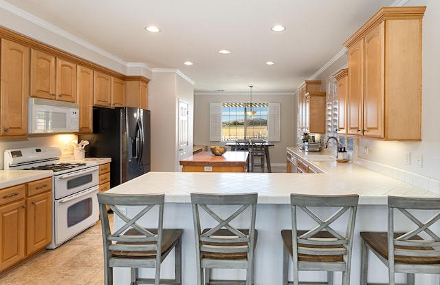 kitchen featuring a breakfast bar, tile counters, ornamental molding, white appliances, and a peninsula