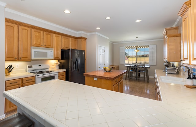 kitchen featuring white appliances, a sink, ornamental molding, tile counters, and a center island