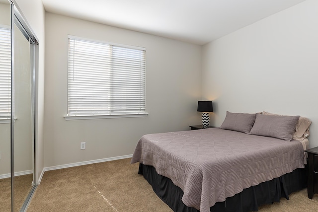 bedroom with light carpet, baseboards, and a closet