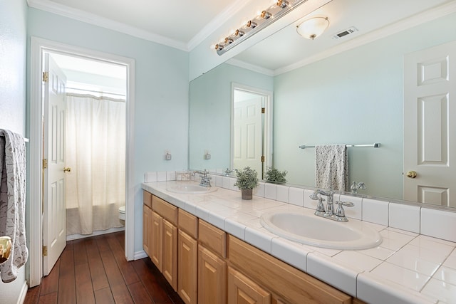 bathroom featuring ornamental molding, wood finished floors, a sink, and visible vents