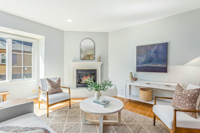 living area with recessed lighting, baseboards, wood finished floors, and a glass covered fireplace