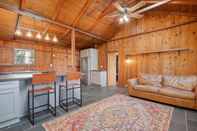 living room featuring lofted ceiling with beams, wood ceiling, wooden walls, and ceiling fan