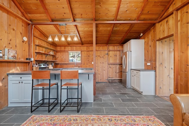 kitchen featuring wooden walls, wood ceiling, freestanding refrigerator, open shelves, and a kitchen bar