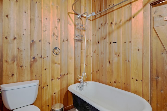 full bath with a freestanding tub, toilet, and wooden walls