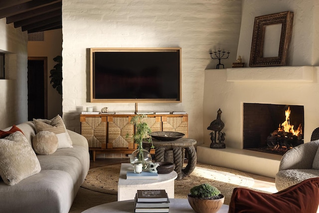 living area with a warm lit fireplace and beam ceiling