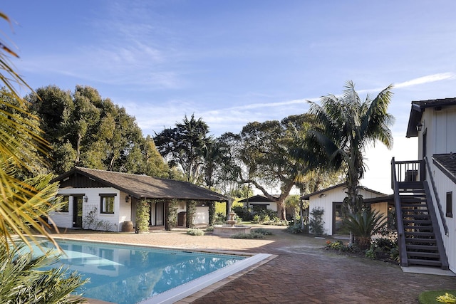 pool featuring a patio area, stairway, and an outdoor structure