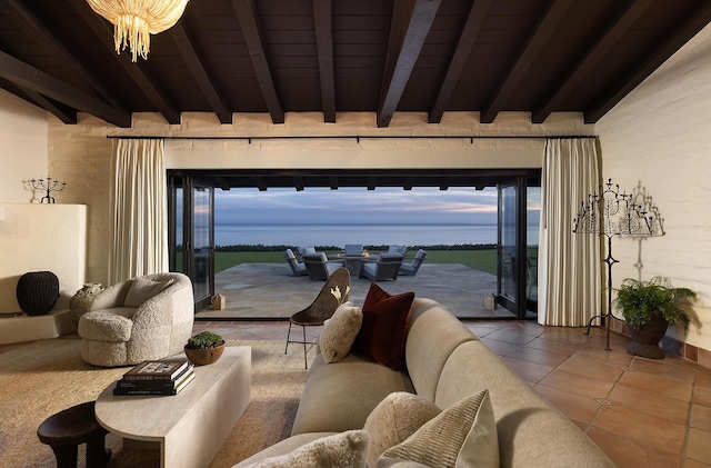 living area with beam ceiling, plenty of natural light, an inviting chandelier, and tile patterned floors