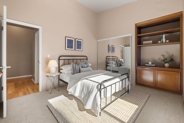 bedroom with a closet, light colored carpet, and a towering ceiling