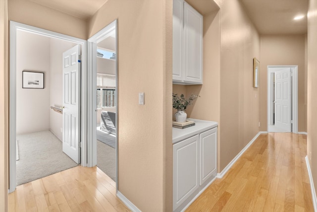 hallway featuring baseboards and light wood finished floors