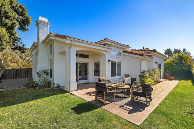 rear view of property featuring a tile roof, a yard, a patio, a chimney, and fence