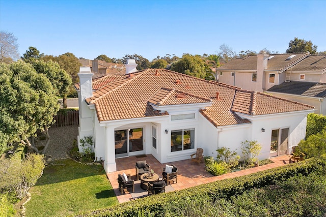 back of house with a chimney, a tiled roof, fence, a yard, and a patio area