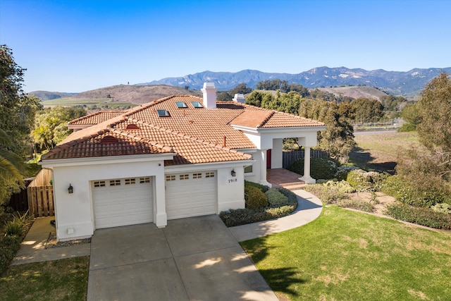 mediterranean / spanish home featuring fence, a tiled roof, an attached garage, and a mountain view