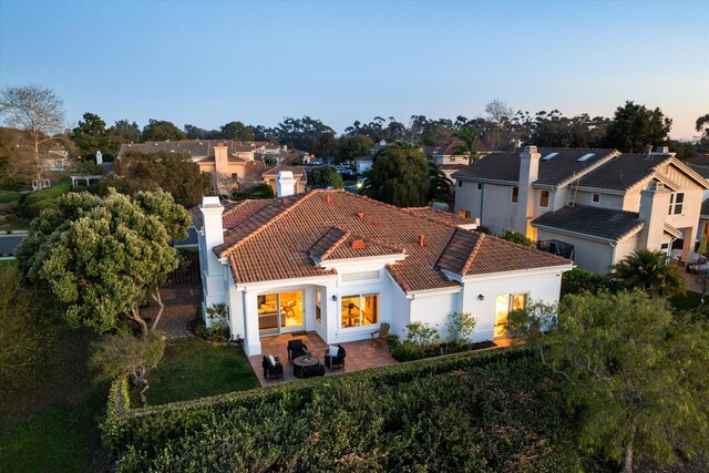 rear view of house with a patio area, a tile roof, a residential view, and stucco siding