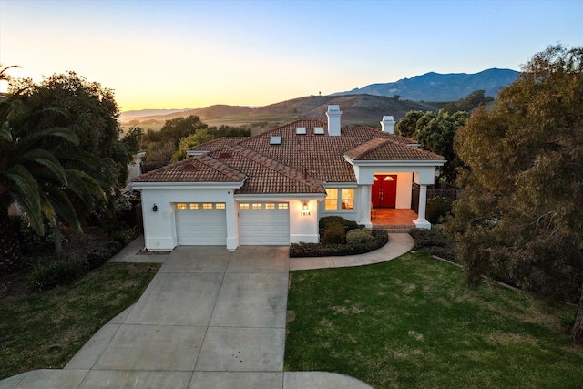 mediterranean / spanish-style house featuring a garage, a front lawn, a tile roof, and stucco siding