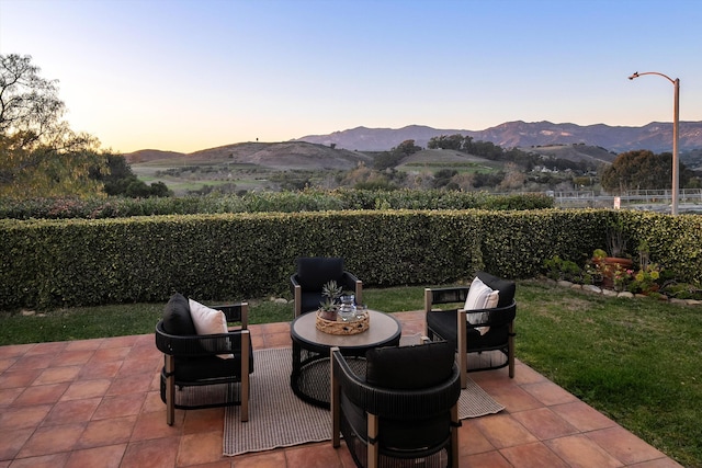 patio terrace at dusk with a fenced backyard and a mountain view