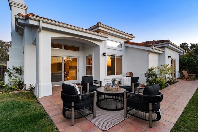 rear view of property featuring stucco siding, a tile roof, a chimney, and a patio