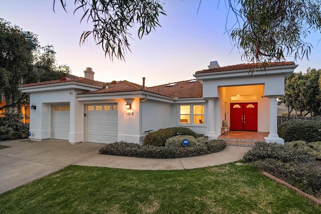 mediterranean / spanish-style home featuring a garage, a chimney, concrete driveway, and stucco siding