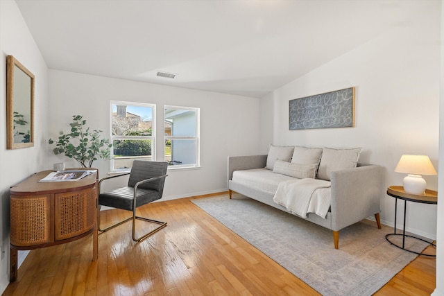 office space with visible vents, vaulted ceiling, baseboards, and hardwood / wood-style flooring