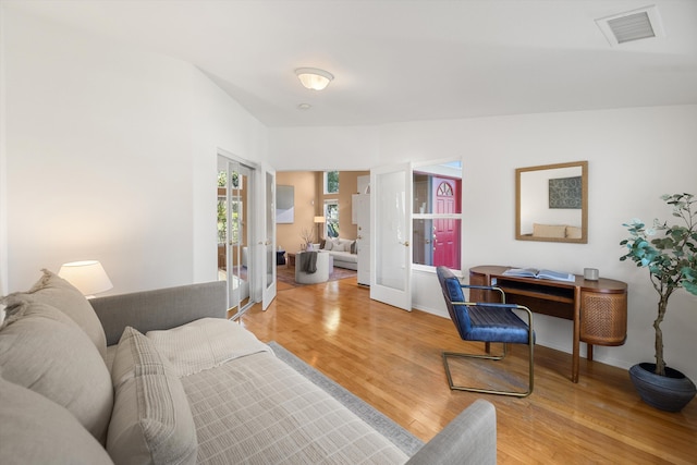 living room with french doors, wood finished floors, visible vents, and baseboards